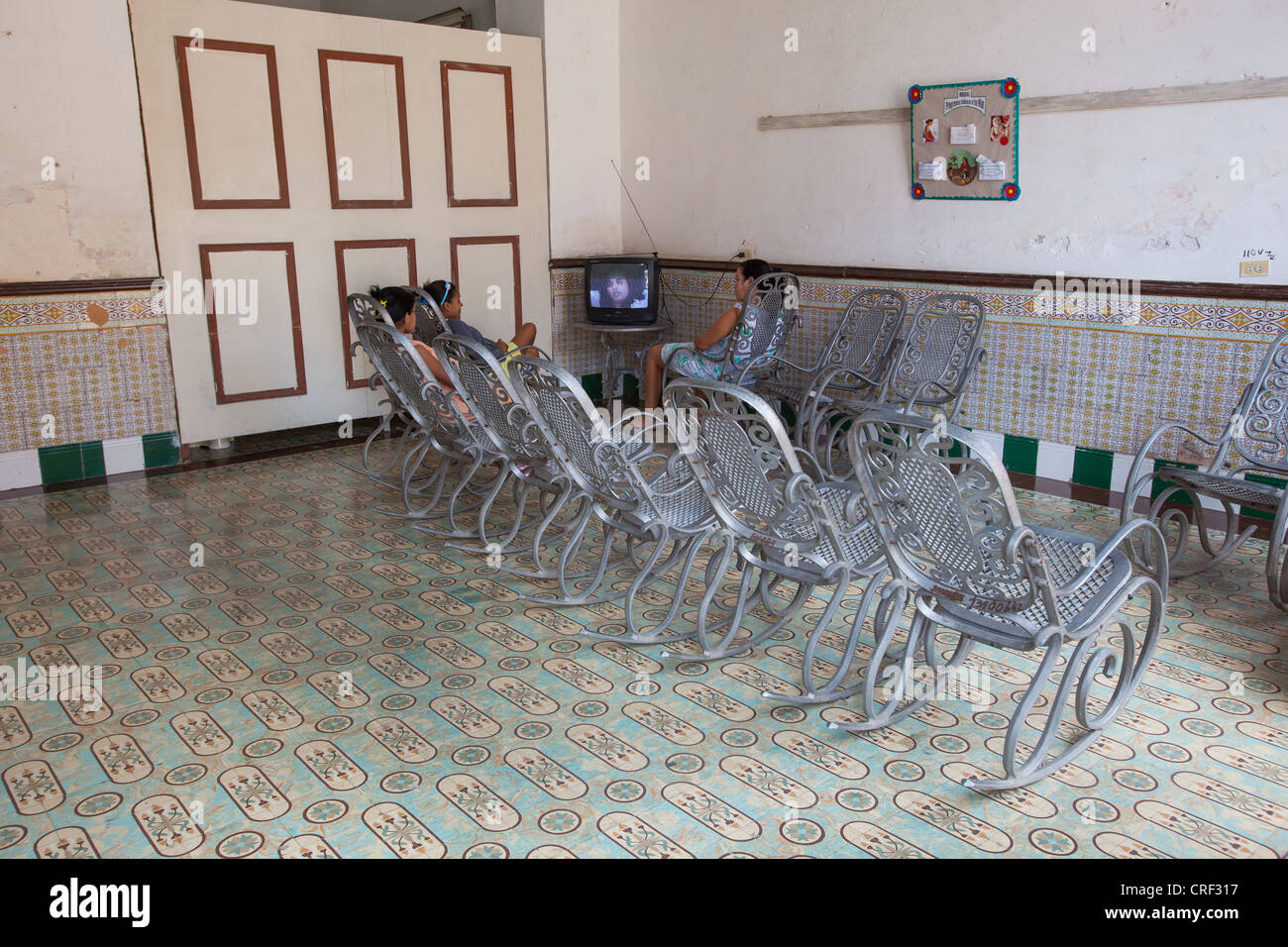 Women sitting in wrought iron rocking chairs watching TV in Trinidad, Cuba. Stock Photo