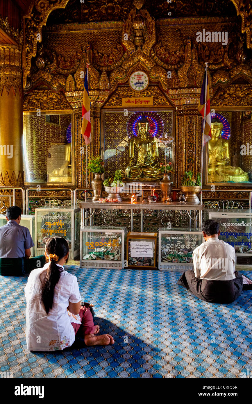 Myanmar, Burma, Yangon. Sule Pagoda. Early-Morning Worshipers Praying at Buddha Shrine. Stock Photo