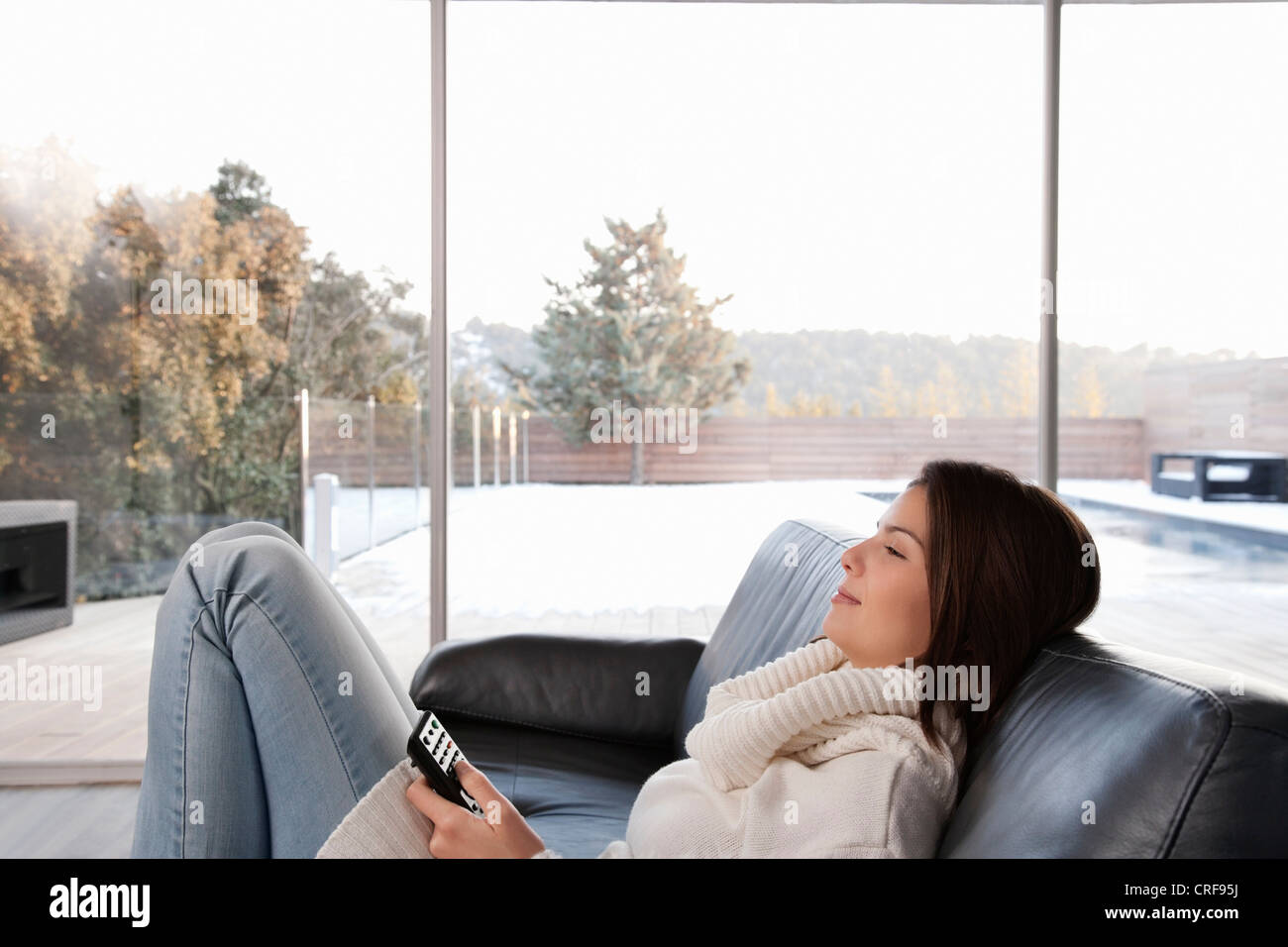 Woman relaxing on sofa in living room Stock Photo - Alamy