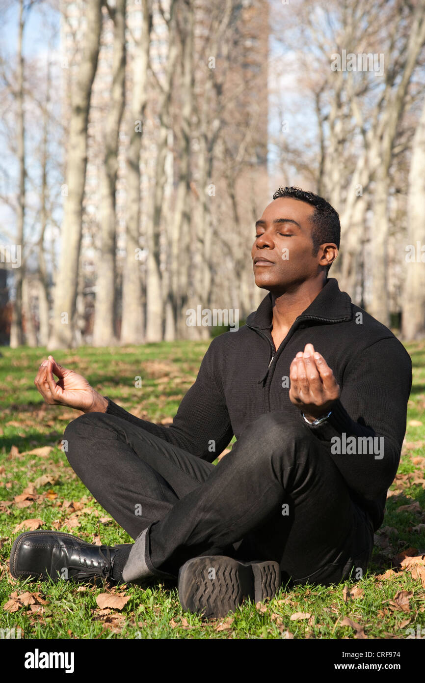 African American businessman sitting in lotus position on grass Stock Photo