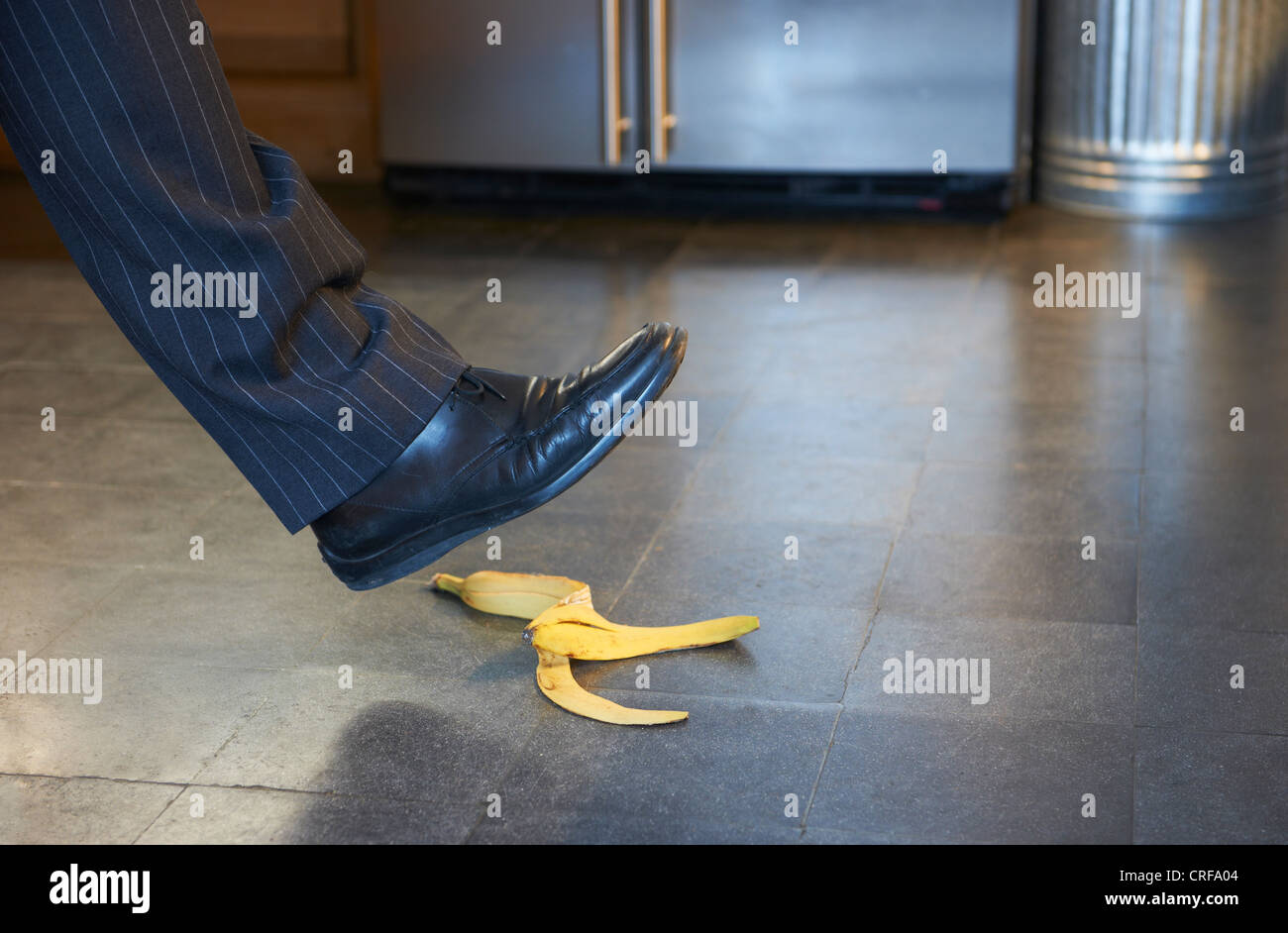 Businessman stepping on banana peel Stock Photo
