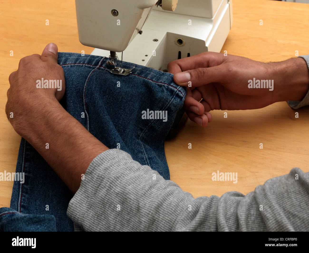 man sewing hemming jeans