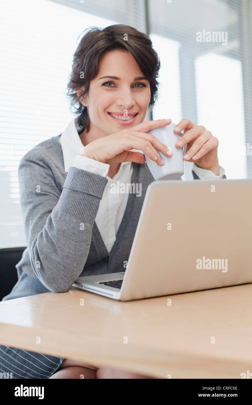 Businesswoman drinking coffee at desk Stock Photo Alamy