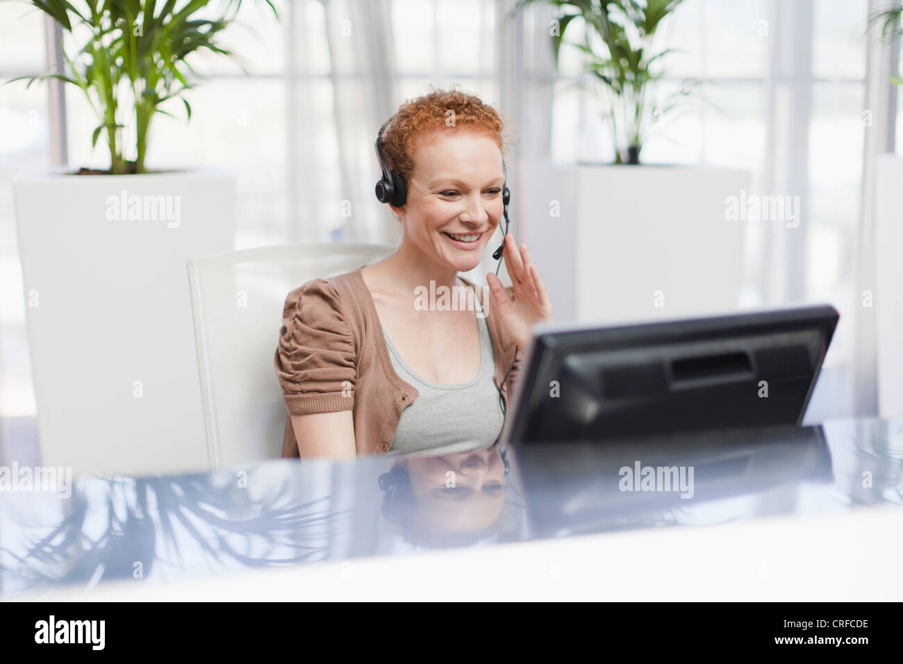 Receptionist wearing headset at desk Stock Photo Alamy
