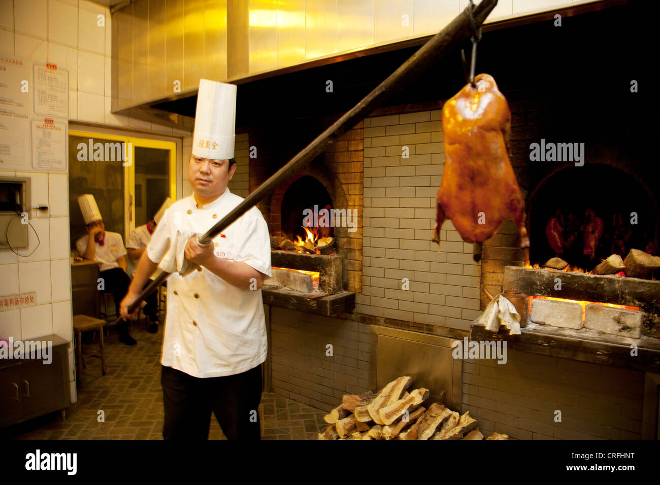 Duck chef lifts ducks in and out of the ovens. Quanjude roast duck restaurant in Wangfujing, Beijing Stock Photo