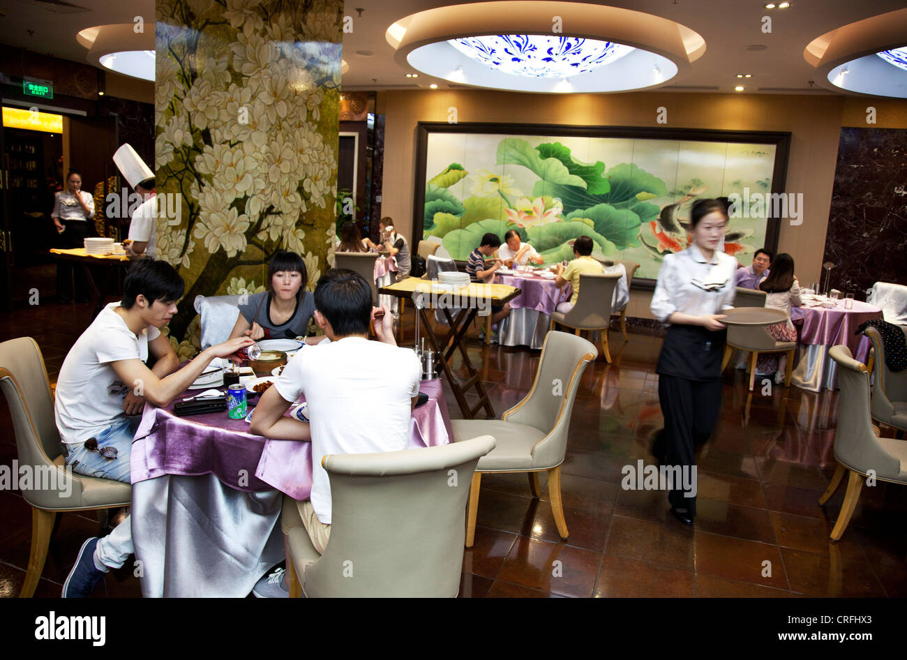 Waiting staff and customers in the main dining room. Quanjude roast duck restaurant in Wangfujing, Beijing. Stock Photo