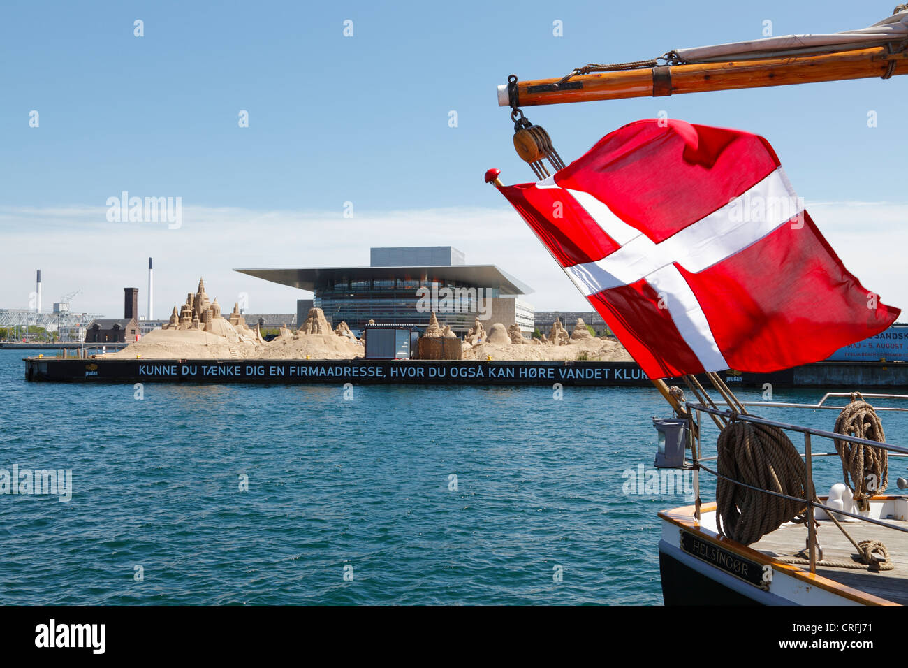 Copenhagen International Sand Sculpture Festival and the Opera in Copenhagen seen through flag on a moored vintage sailing ship Stock Photo