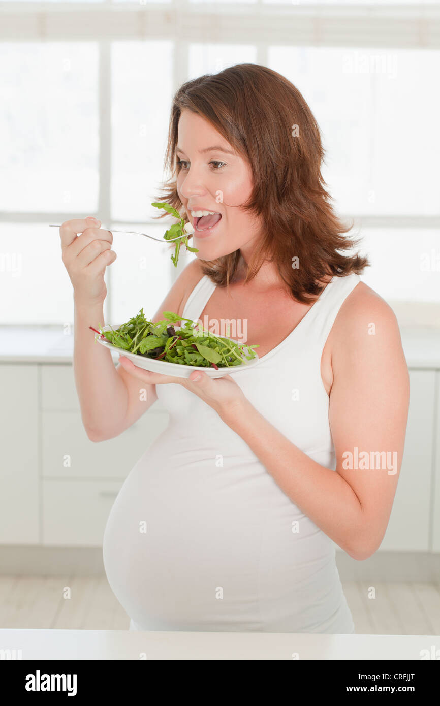 Pregnant woman eating salad in kitchen Stock Photo Alamy