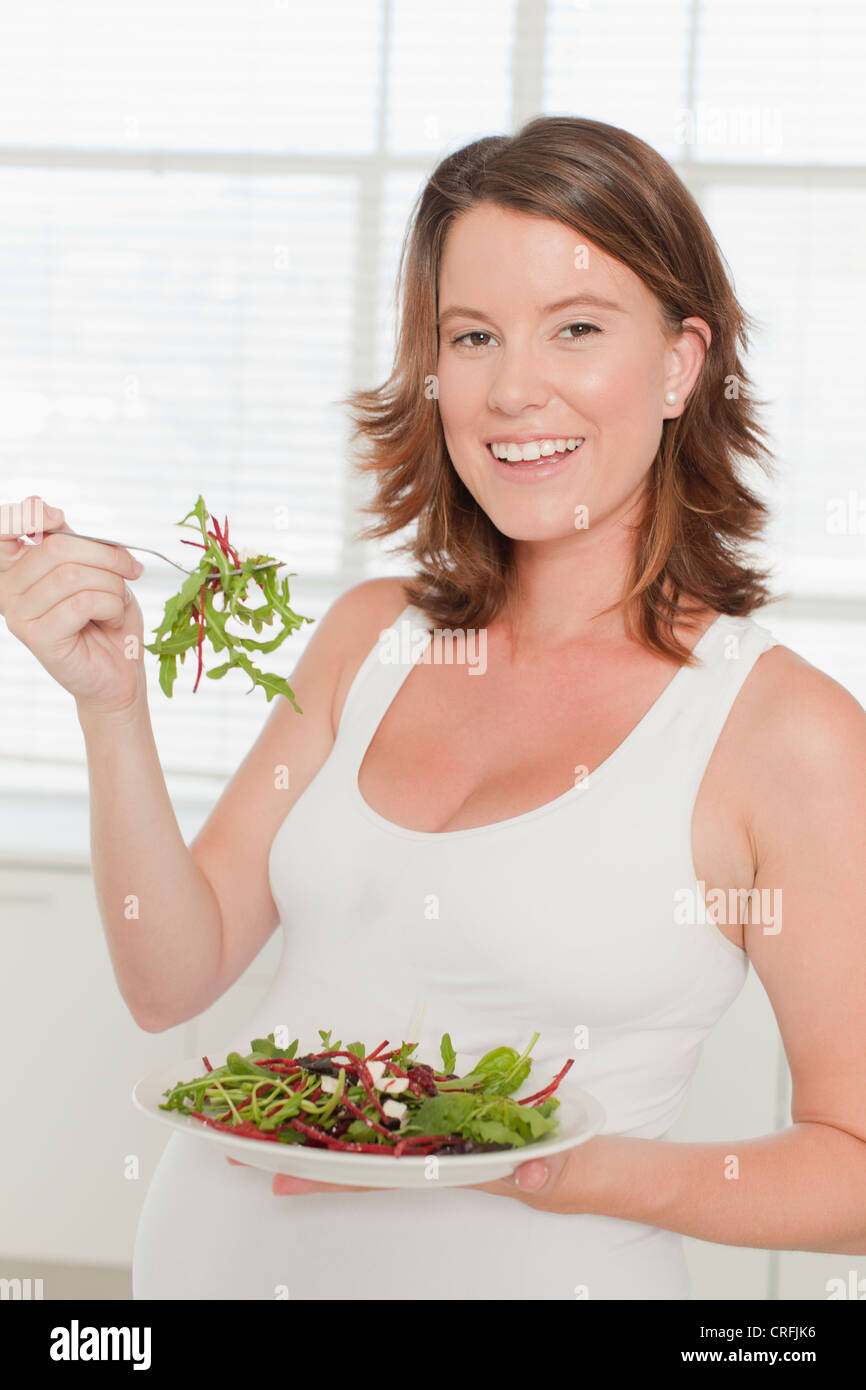 Pregnant woman eating salad in kitchen Stock Photo Alamy