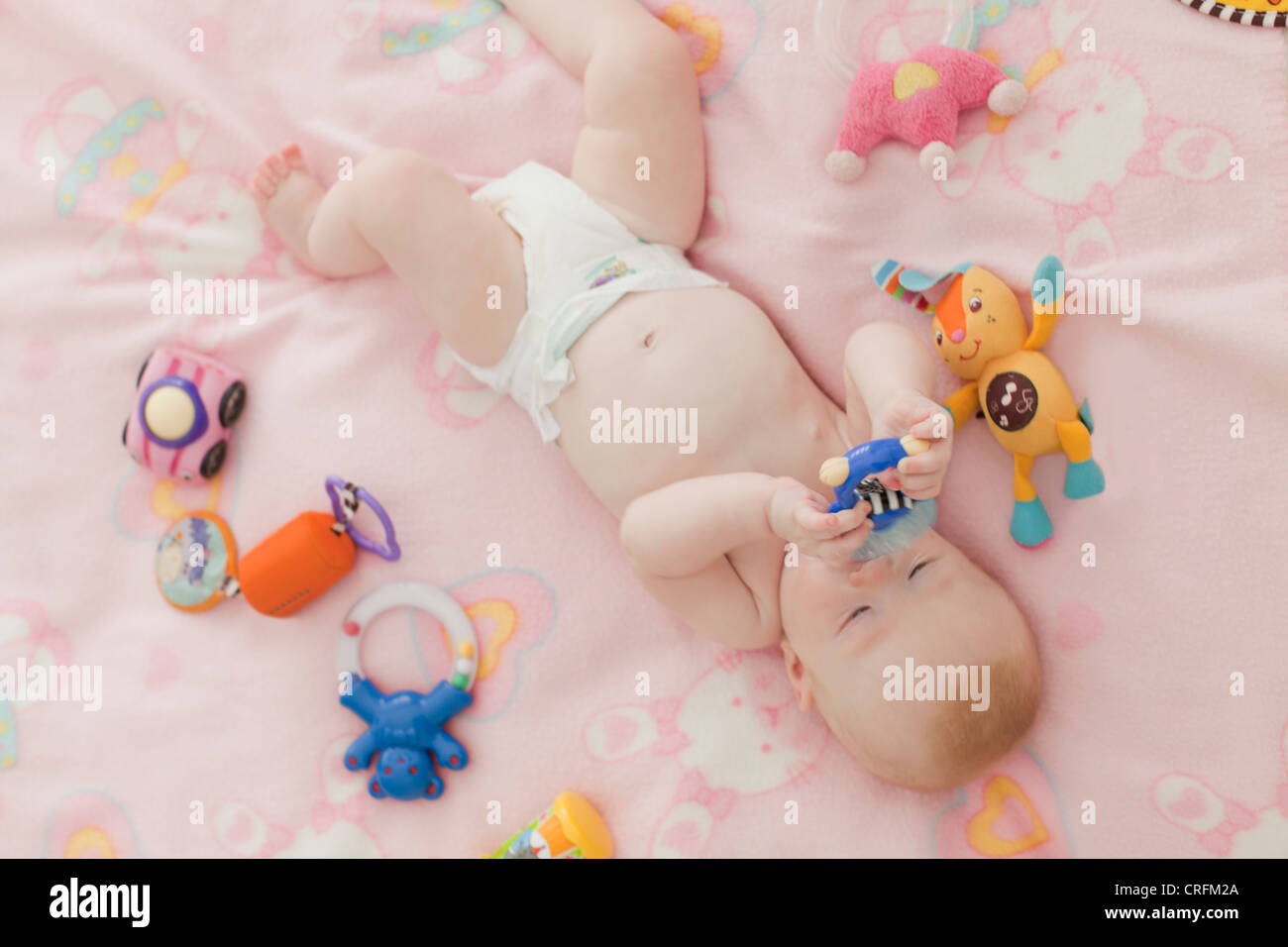 Baby chewing on rattle on blanket Stock Photo