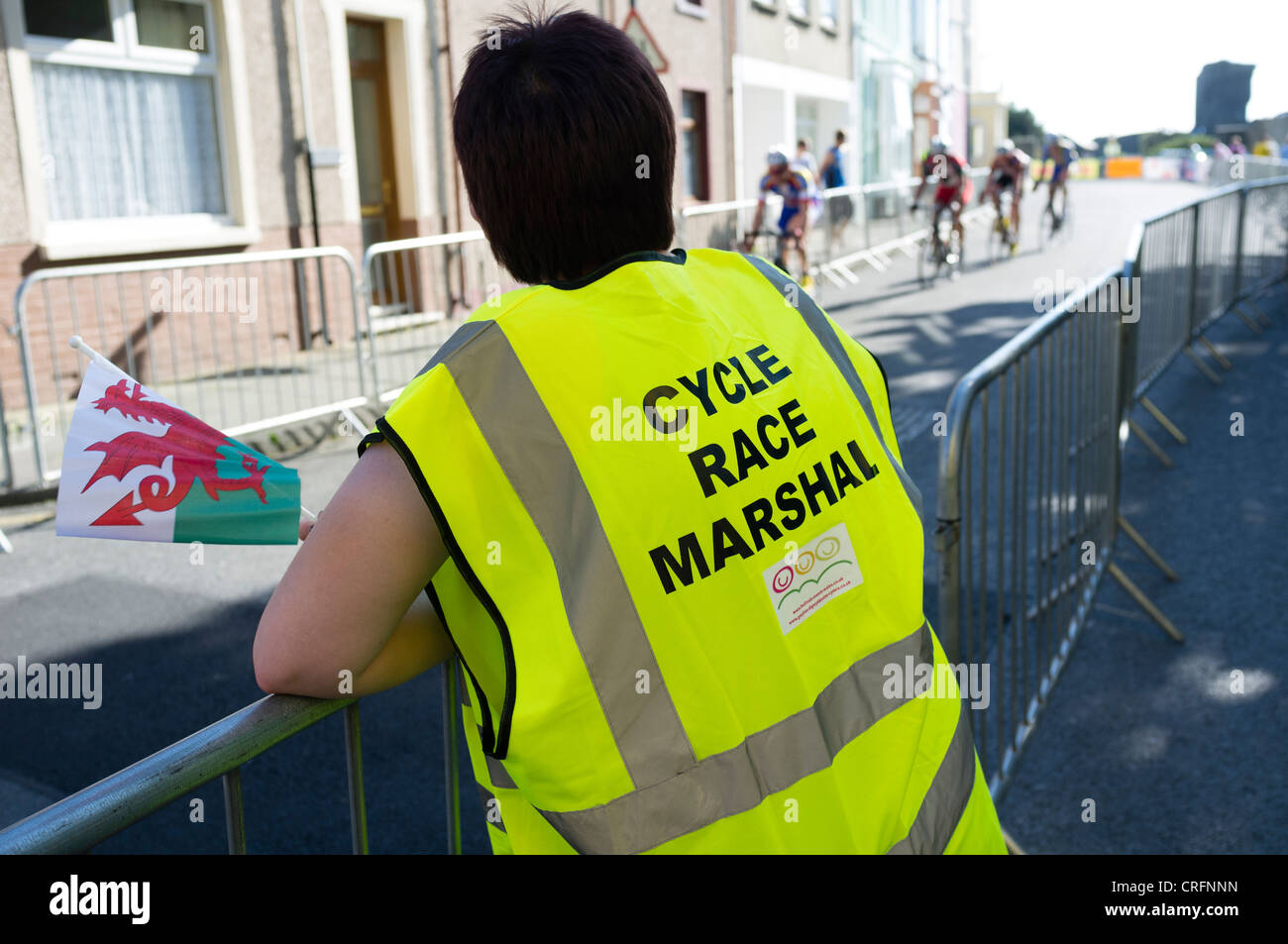 A cycle race marshal wearing a hi-vis yellow tabard at the Halfords tour cycle race through the streets of Aberystwyth Wales UK Stock Photo