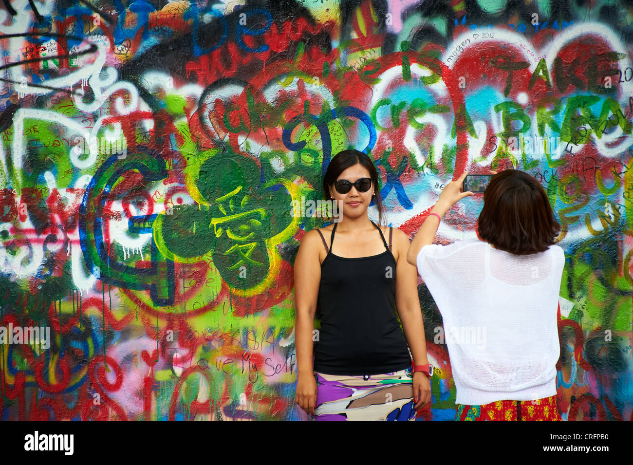 The John Lennon graffiti Wall in Prague, Czech Republic, tourist woman take a photo of  friend Stock Photo