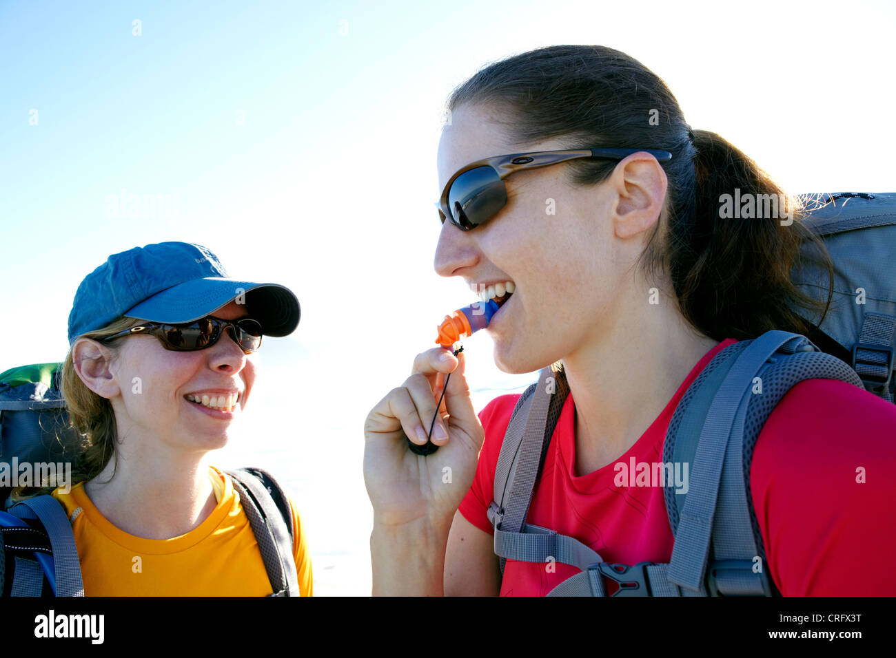 Two women laughing while drinking from their hydration packs. Noordhoek