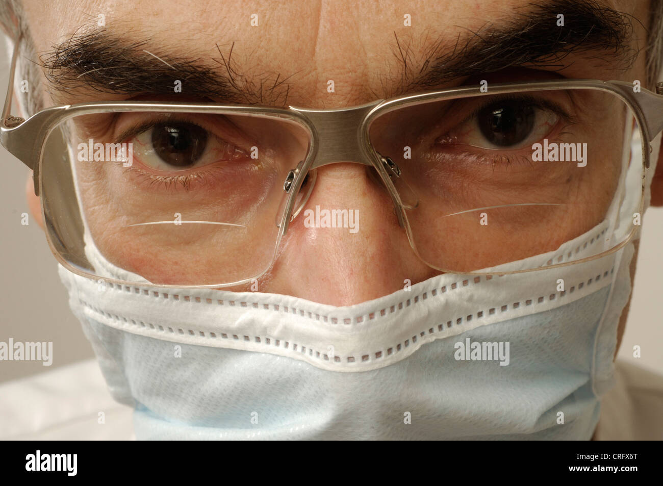 Facial closeup of a dental surgeon wearing a surgical mask and