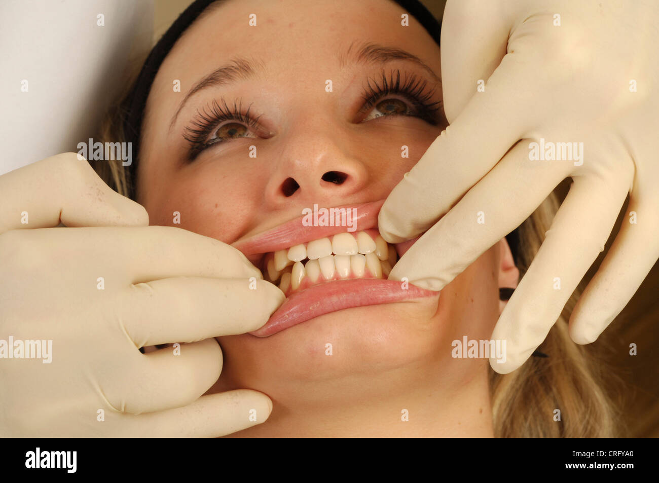 A dentist examines the front teeth and gums of a young girl during a