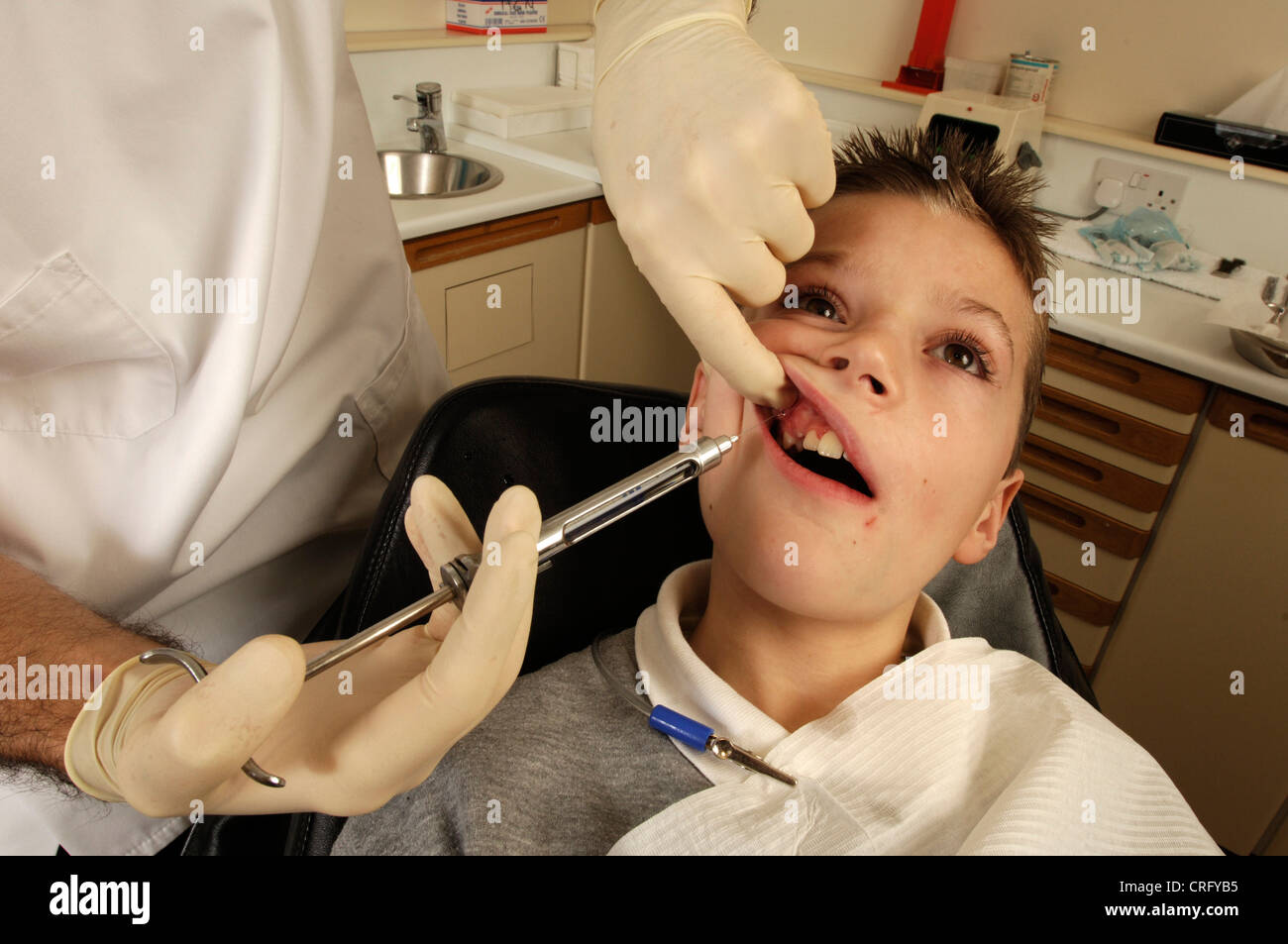Dentist injecting a local pain killing anaesthetic into the gums of a