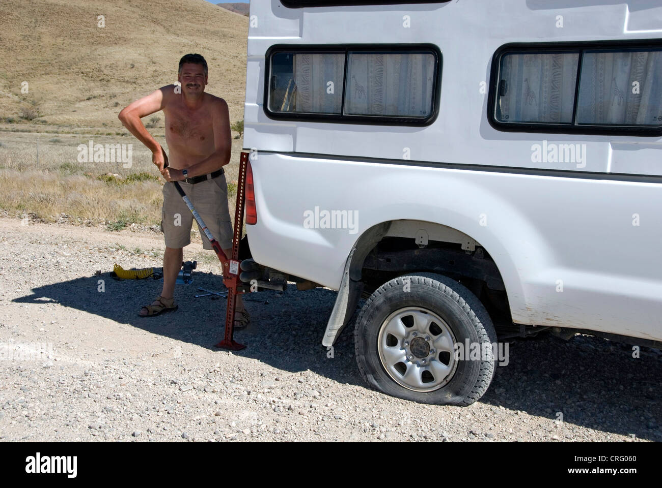 man with HiJack, lifting the car to change a flat tyre, Namibia Stock Photo