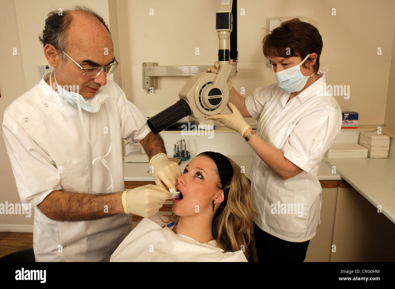 A young girl being prepared for a dental x-ray by a dentist and his assistant. Stock Photo