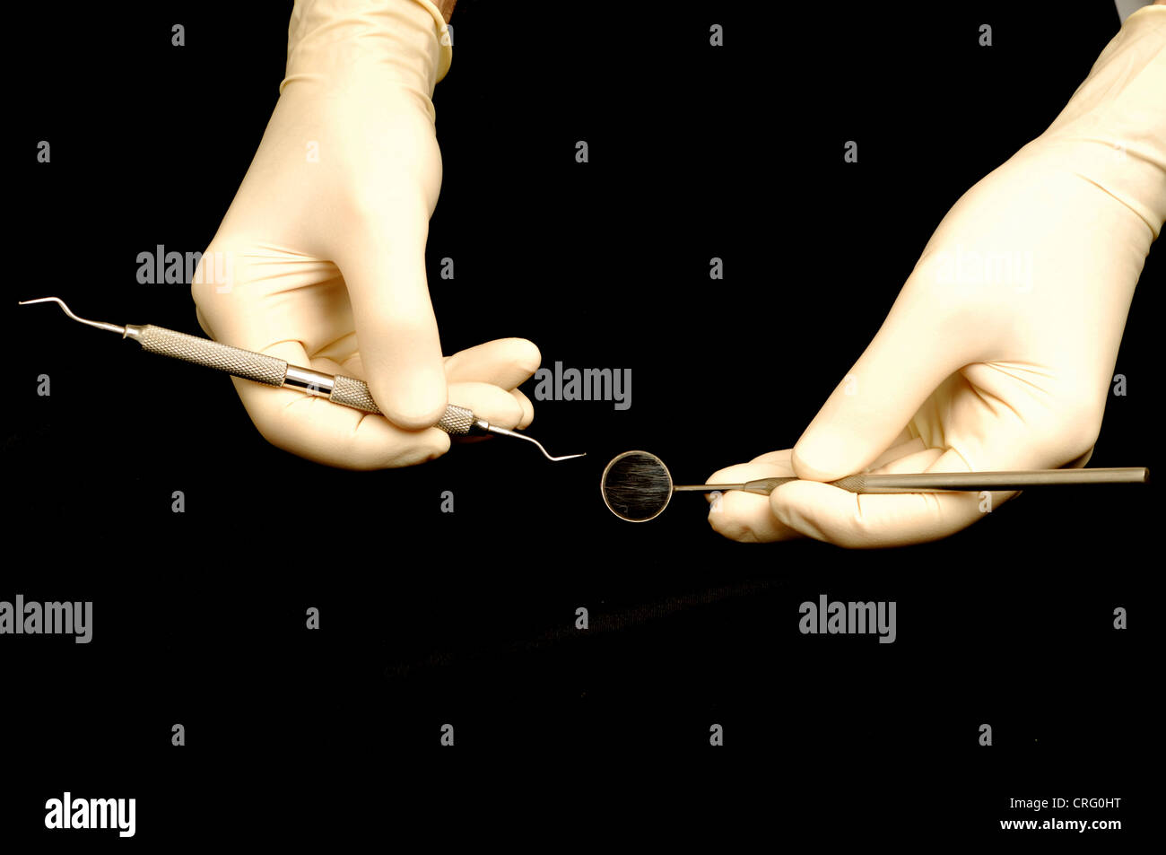 Gloved hands hold a double sided dental pick and dental mirror Stock