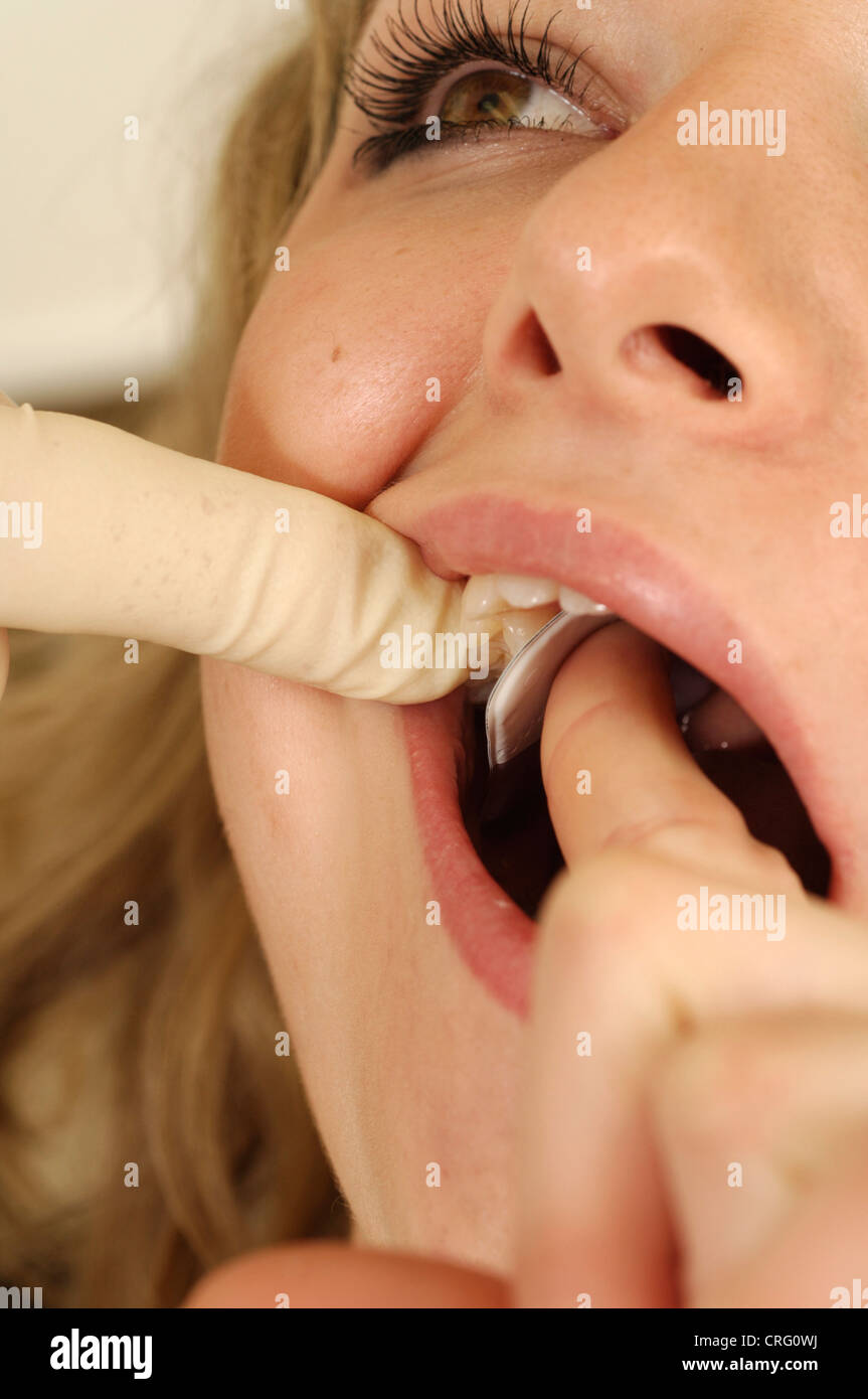 A dentist inserts a bitewing into the mouth of a young female patient. The bite wing is a X-ray film holder that provides a surface to bite down on and hold the X-ray securely in place. Stock Photo