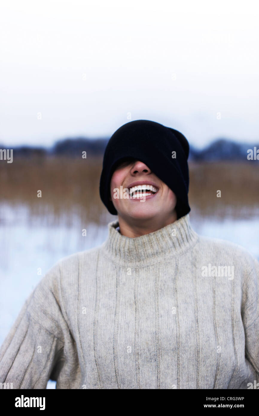 Man wearing hat over eyes in snow Stock Photo