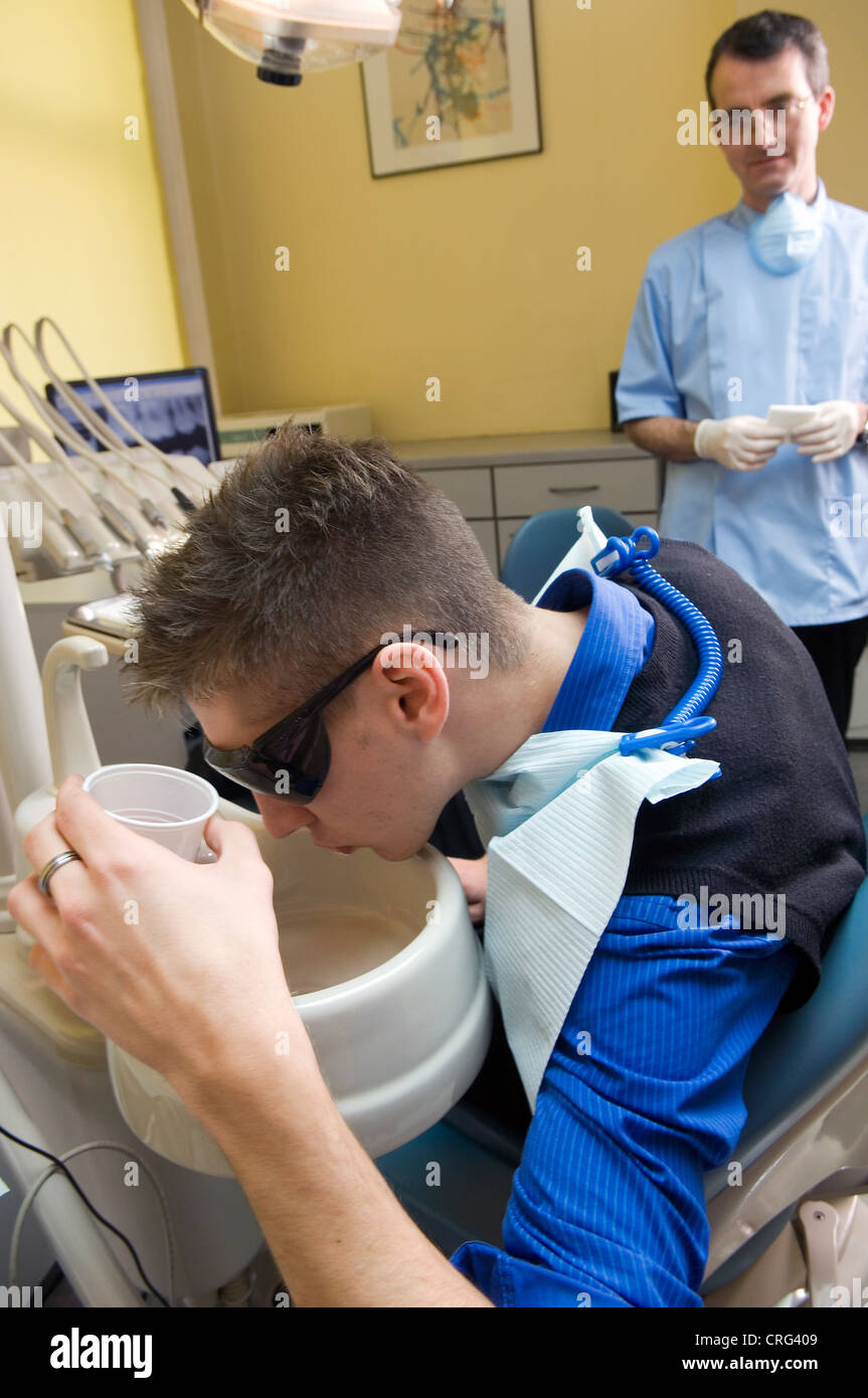 Young male patient rinses his mouth after dental treatment Stock Photo