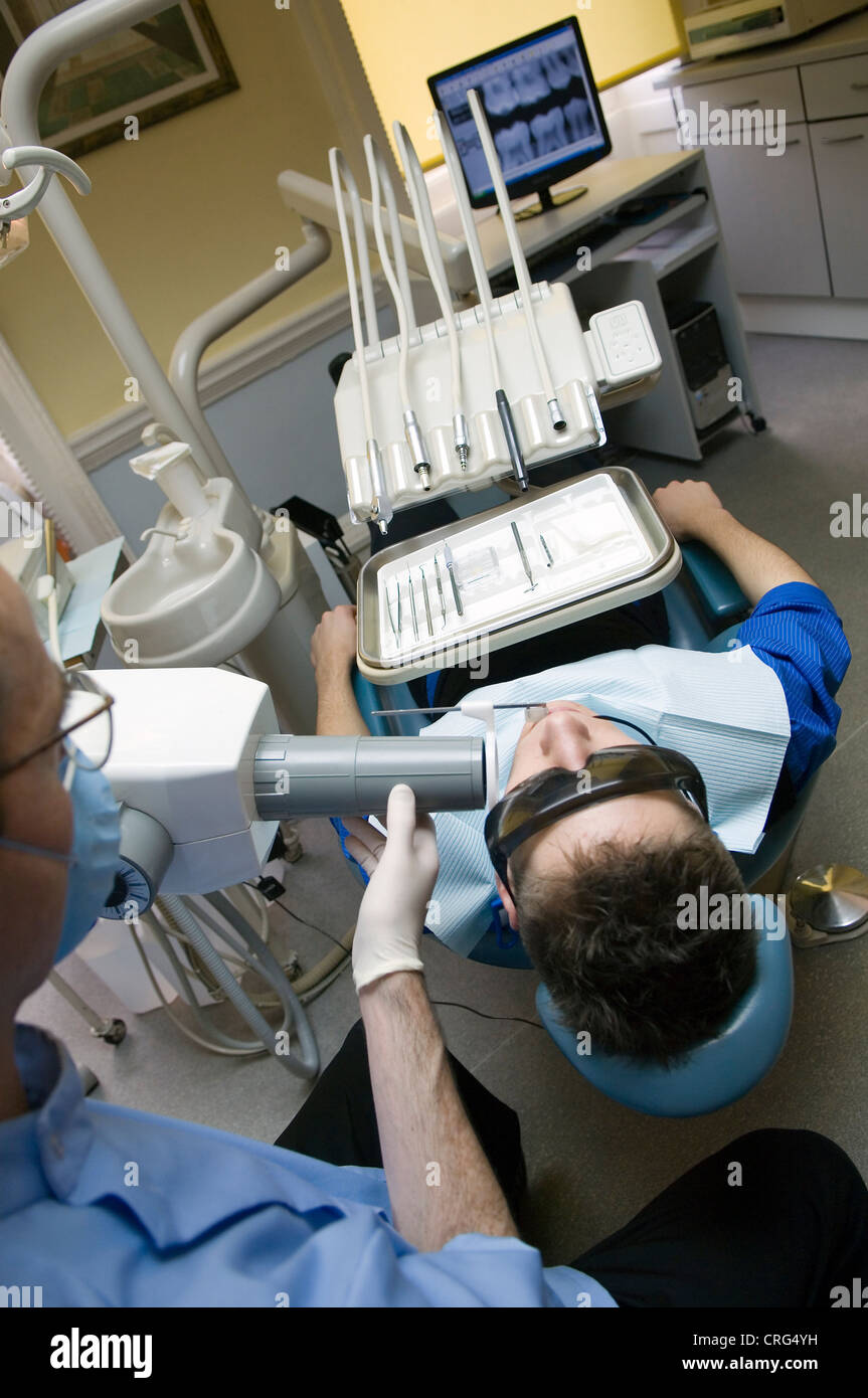 Dentist wearing safety glasses and mouth mask xrays the teeth of young