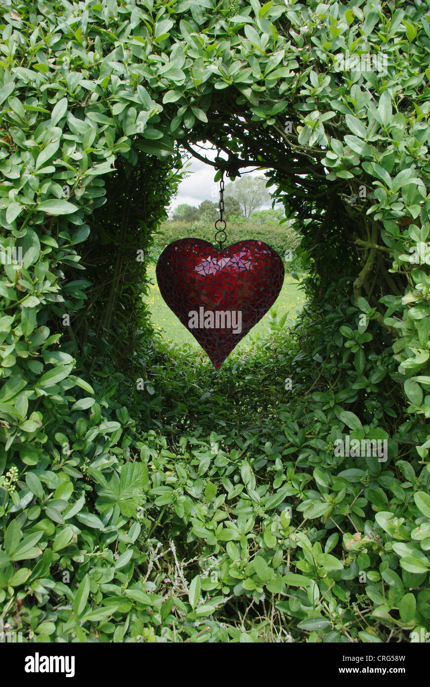 Heartshaped glass garden ornament positioned in a gap in a garden