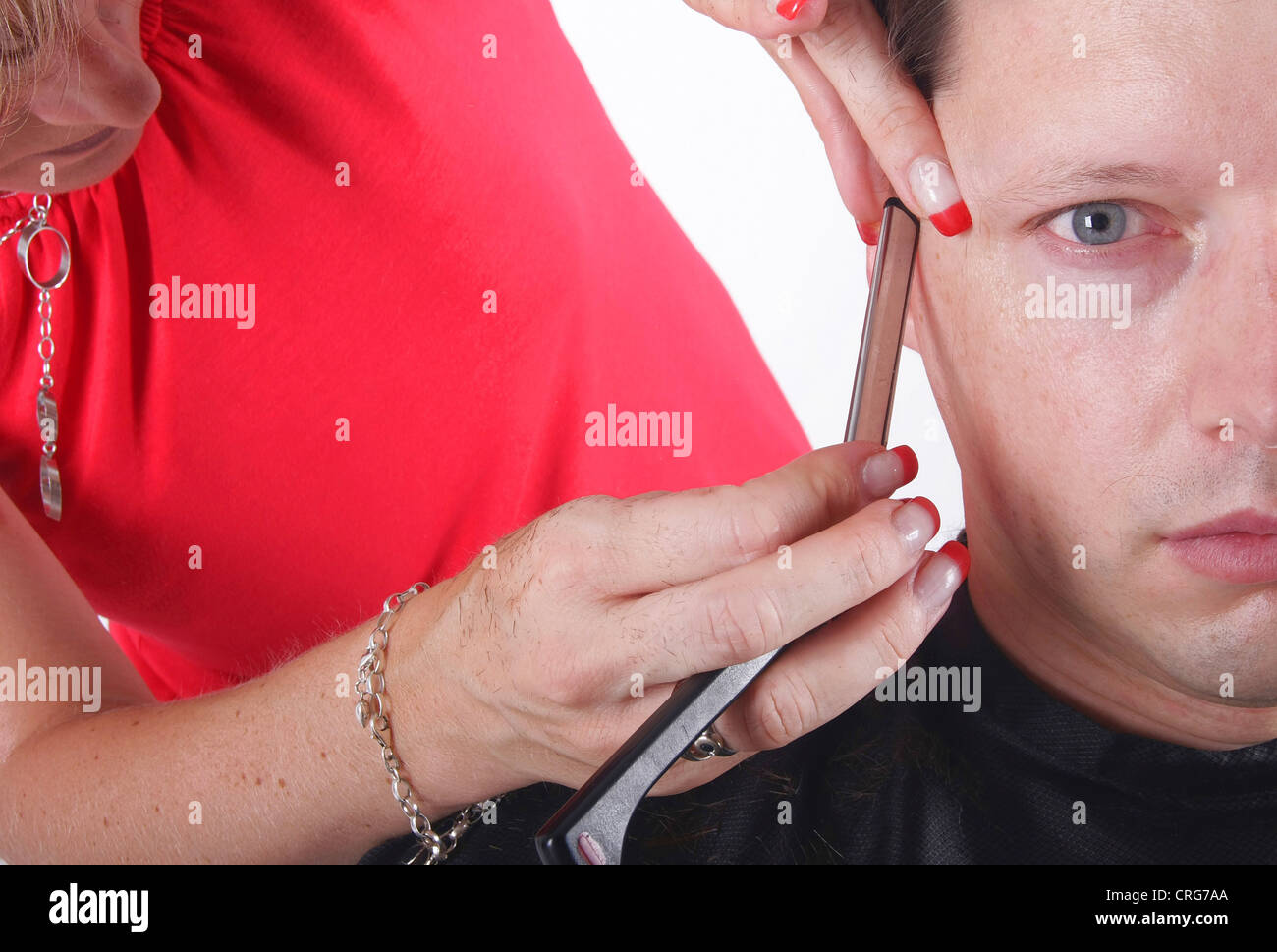 man at hairdresser. The female hairdresser uses a razor Stock Photo