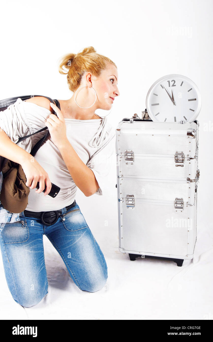 young blond woman under time pressure, looking at a clock Stock Photo