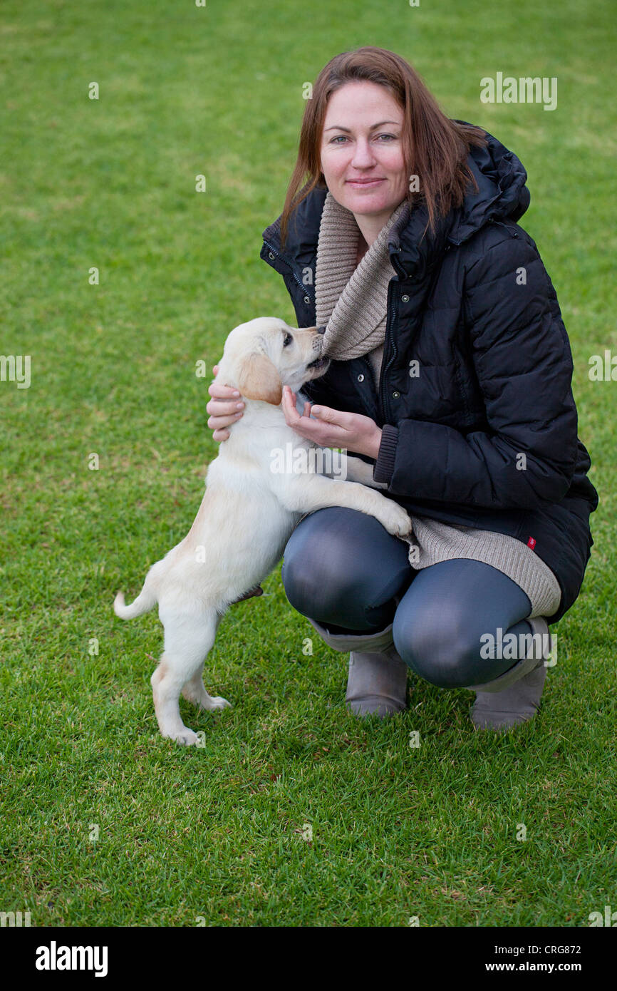 A young lady with her naughty Labrador puppy who is affectionately chewing her jumper Stock Photo