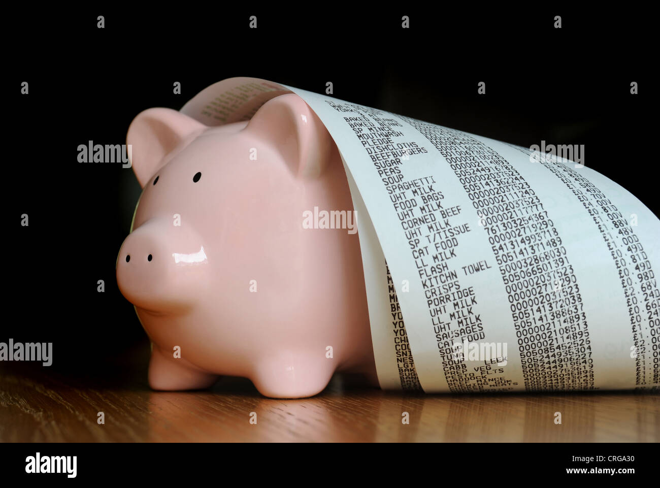 PIGGYBANK WITH SUPERMARKET TILL RECEIPTS RE SHOPPING FOOD BILLS COSTS INCOMES HOUSEHOLD BUDGETS WAGES SAVINGS PRICES ECONOMY UK Stock Photo