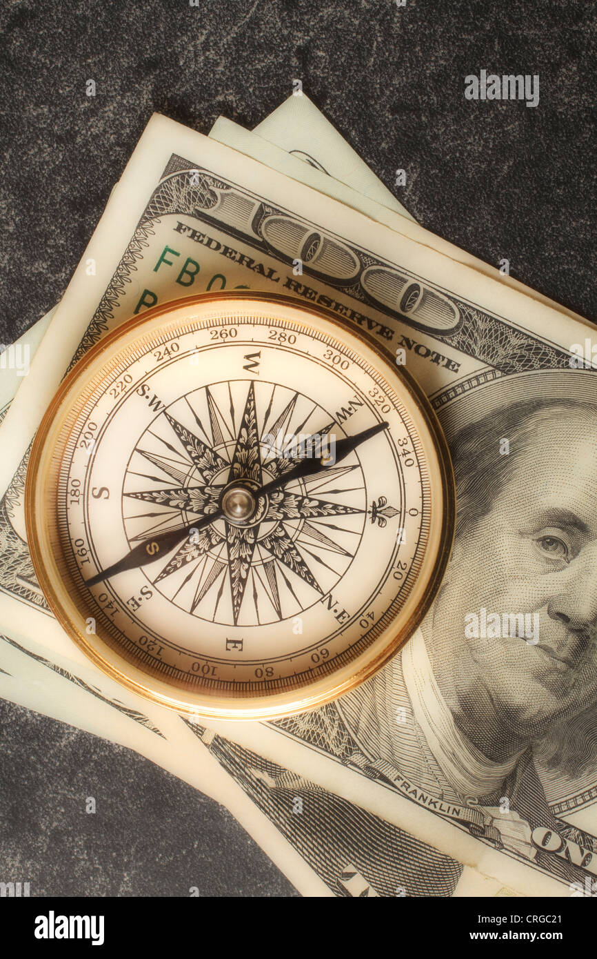 Antique gold compass on an array of US dollars portraying the concept of financial planning. Stock Photo