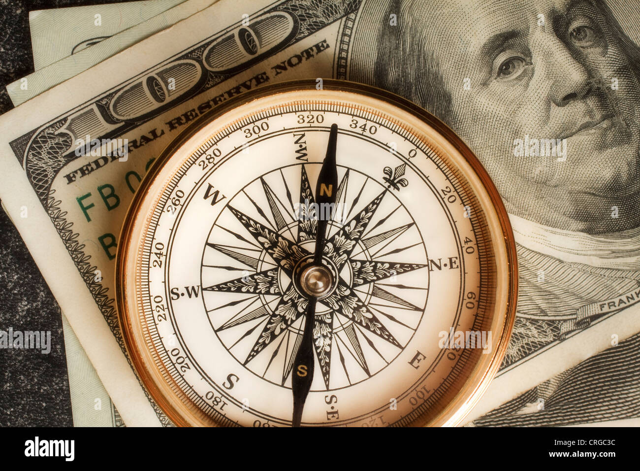 Antique gold compass on an array of US dollars portraying the concept ...