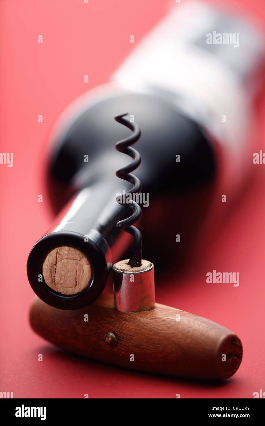 Wine bottle and corkscrew on red background Stock Photo