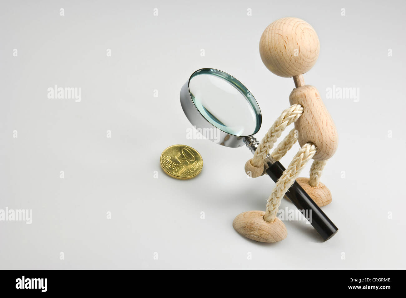 figur examining 50 Euro Cent with a magnifying glass Stock Photo
