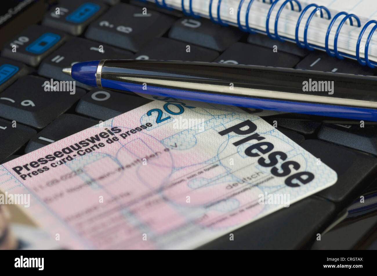 press card, notepad and ball-pen on a computer keyboard Stock Photo