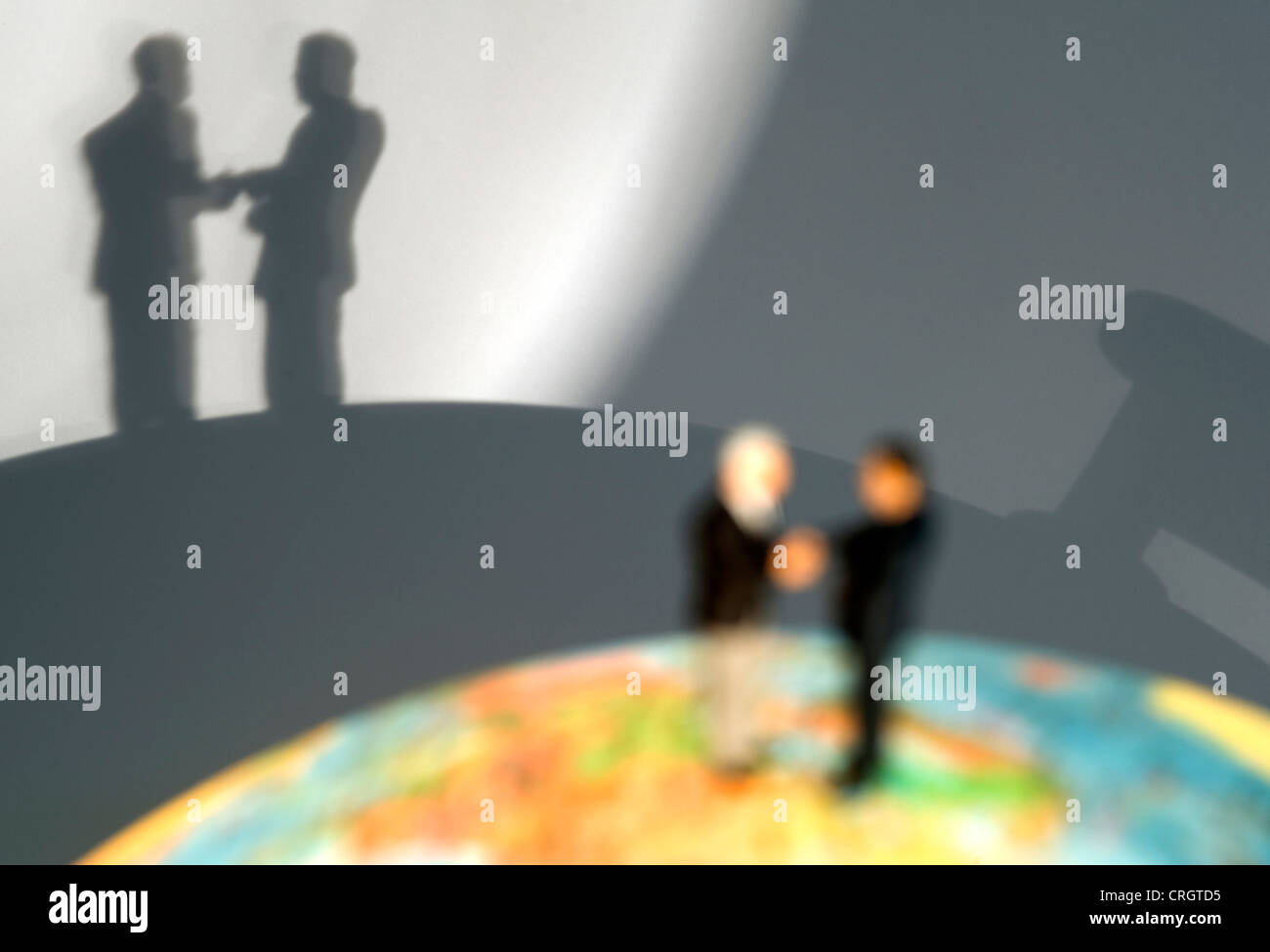symbolic for international economic relations: little figures on a globe shaking hands Stock Photo