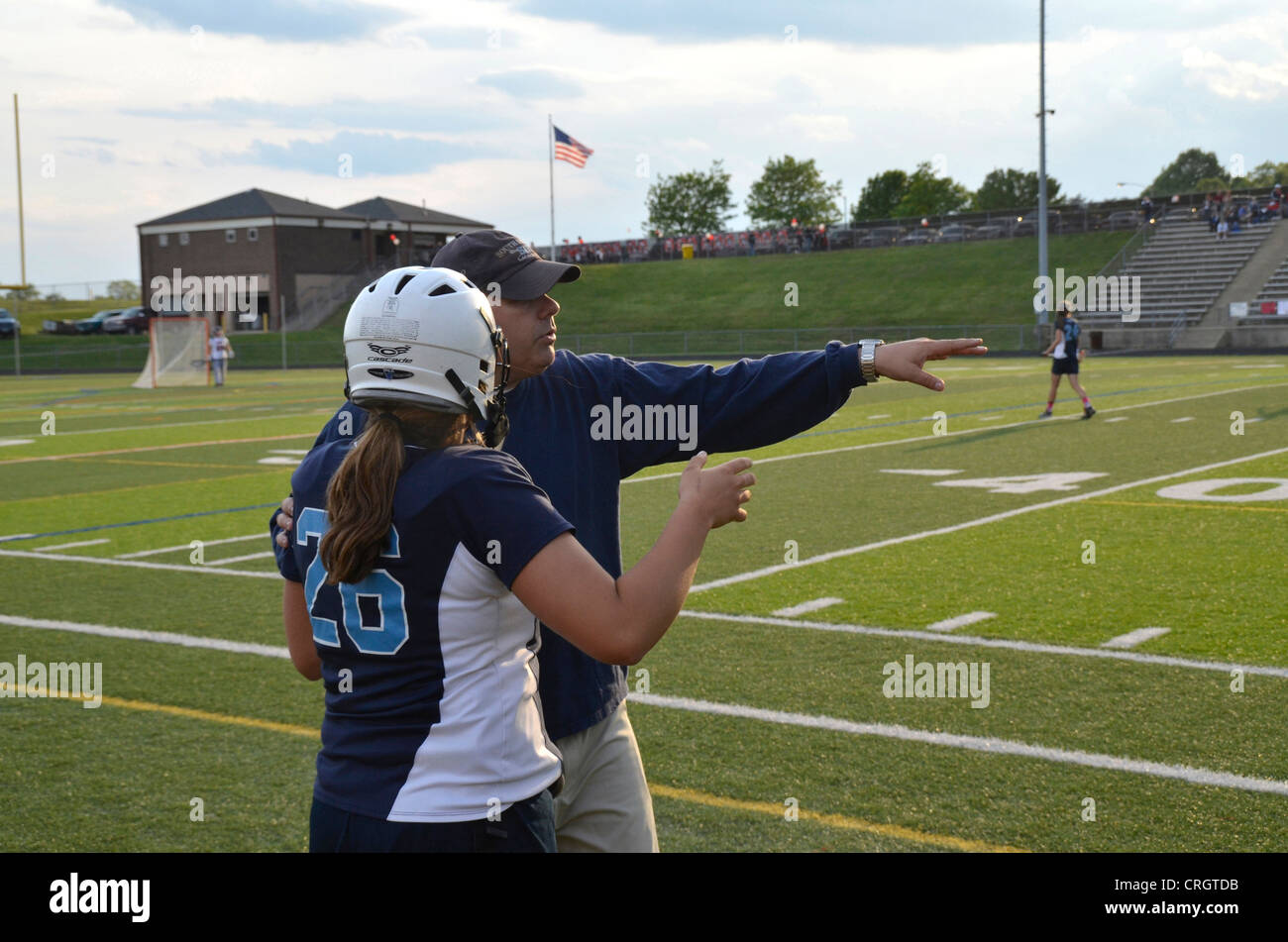 Coach instructs a lacrosse player at a high school girl's lacrosse game