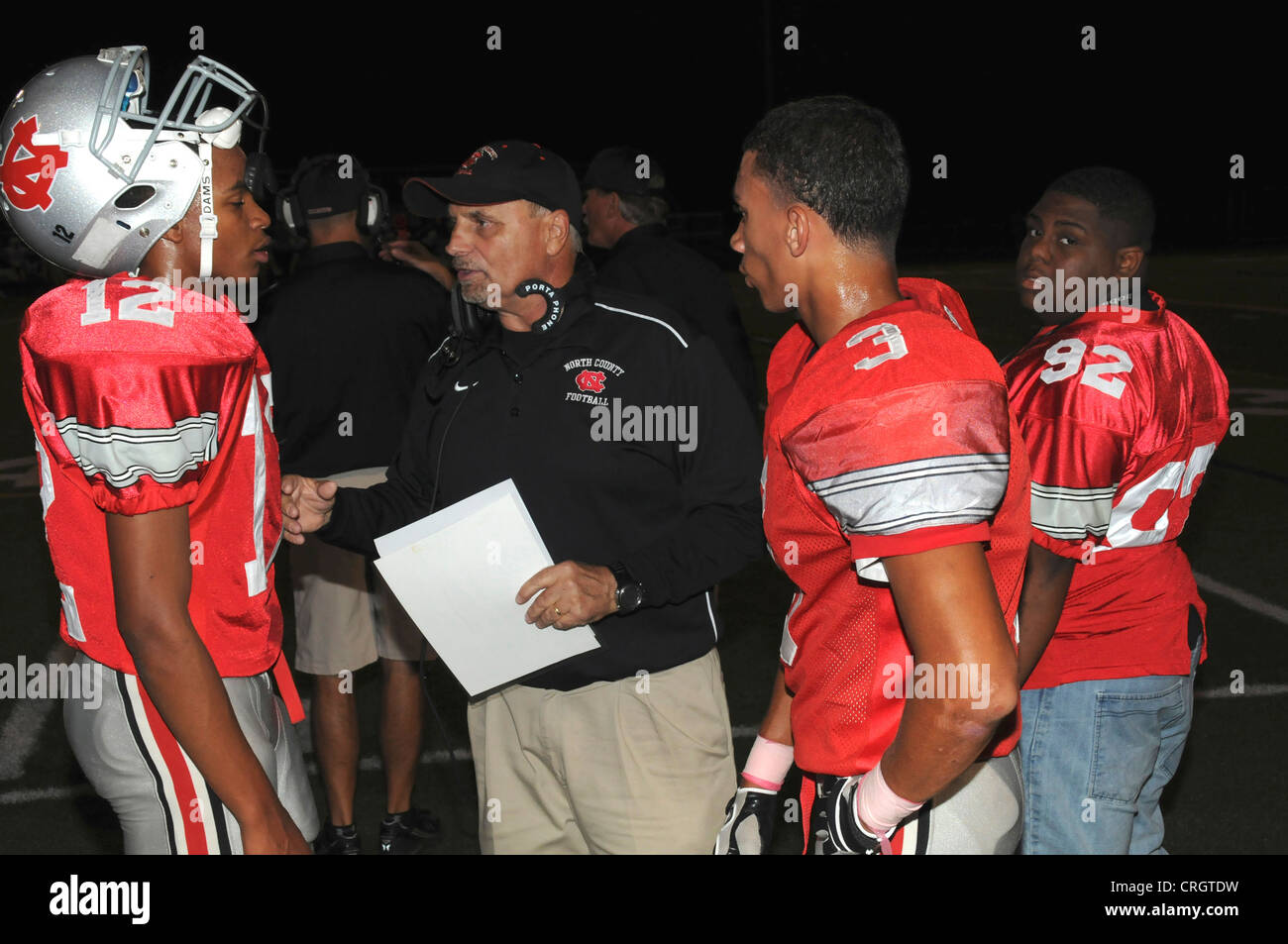Coach giving instructions to his quarterback at a high school game in