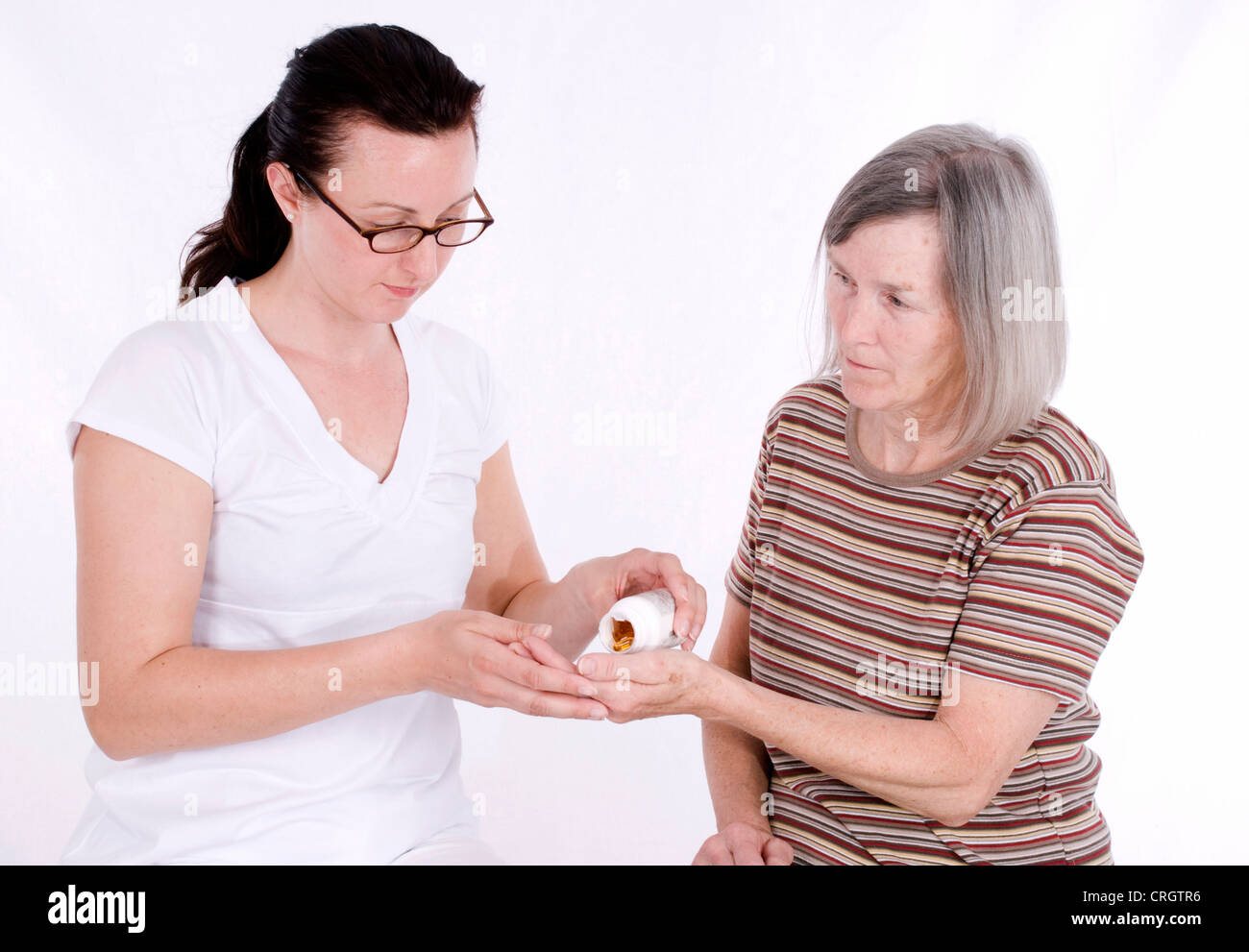 senior woman gets pills from elderly care nurse Stock Photo