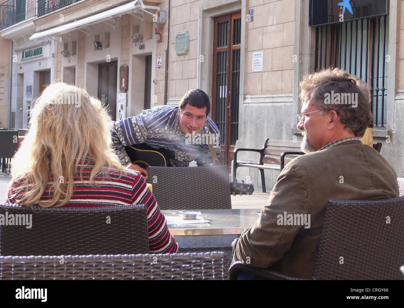 busker seranade a couple at sidewalk cafe, Spain, Balearen, Majorca, Alcudia Stock Photo