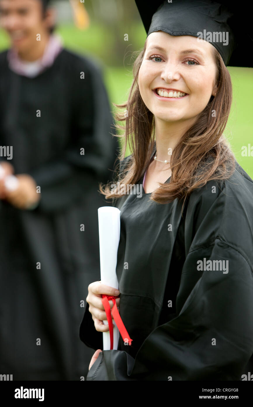 smiling female graduate standing outdoors with her diploma Stock Photo