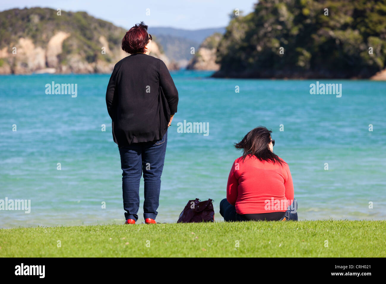 Two ladies on the shore - Bay of Islands, New Zealand Stock Photo
