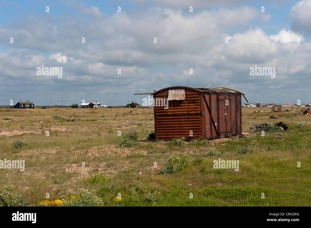 Fisherman's storage hut on the beach at Dungeness, Kent, UK with Derek Jarman's house in the background (to the left of the hut) Stock Photo