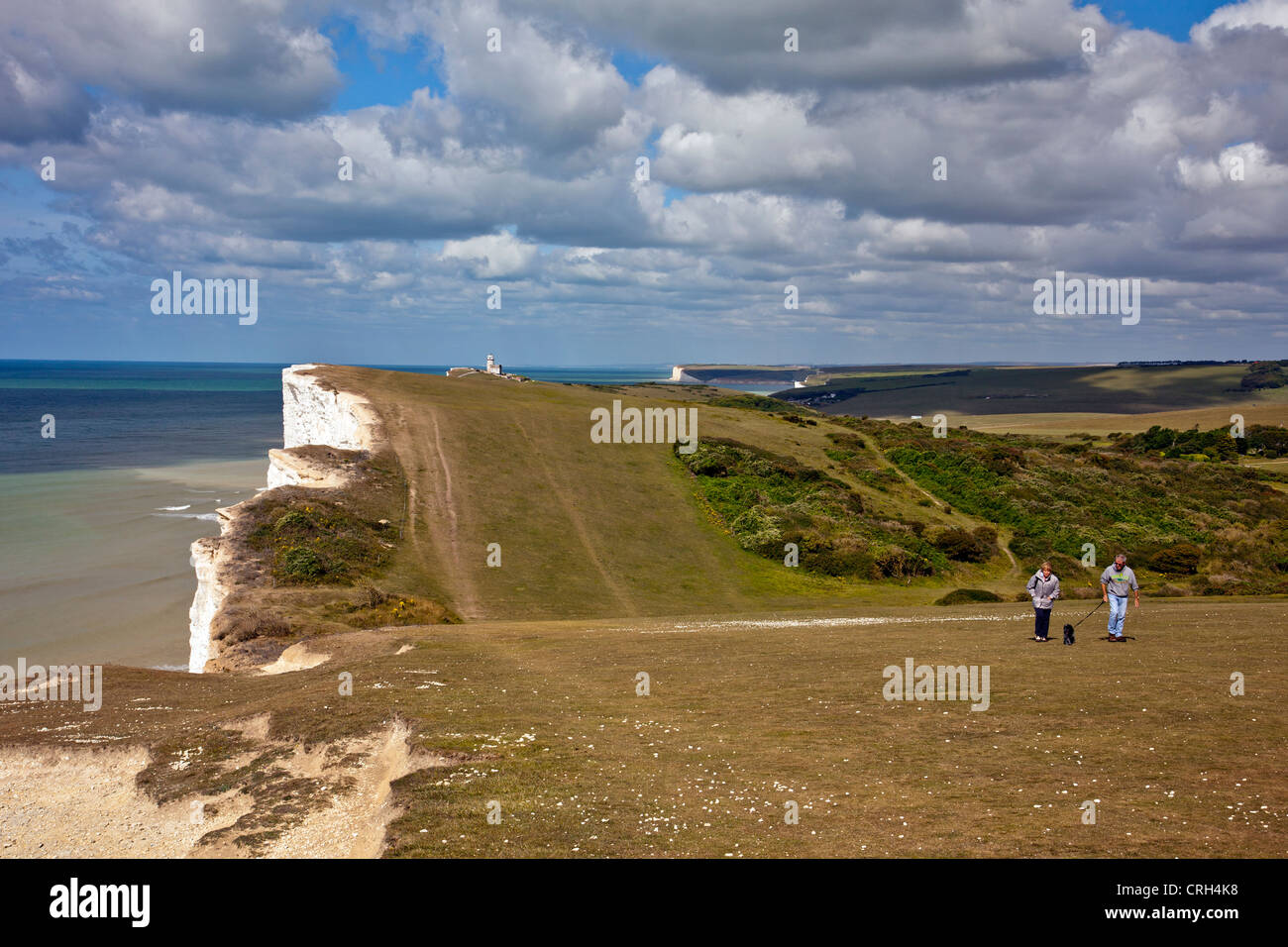 The original Beachy Head lighthouse (1834) at Belle Tout  and two dog walkers on the South Downs Way , East Sussex, England UK Stock Photo
