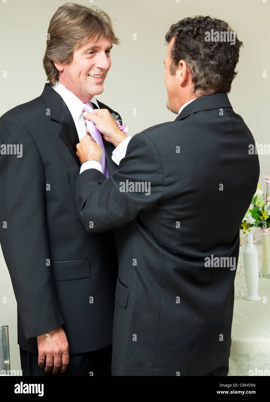One groom straightens the other groom's tie at a gay marriage reception.  Stock Photo