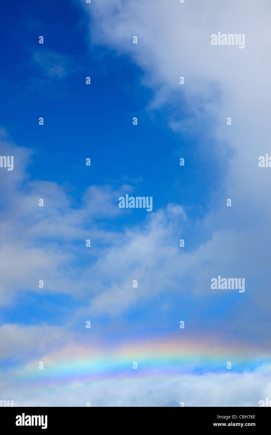 Rainbow across blue sky and white clouds Stock Photo - Alamy