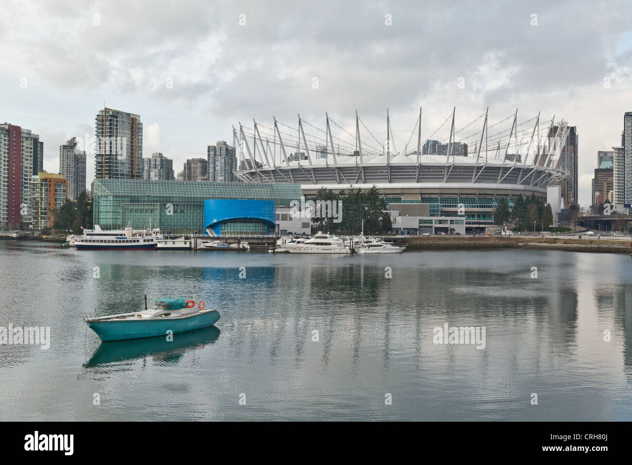 A yacht sits quietly in the water on False Creek Vancouver on a cloudy day just outside BC Place Stadium. Stock Photo