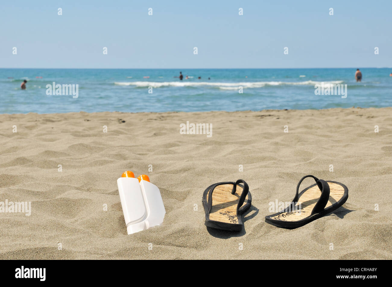 Female slippers and sun cream on beach stock photo Stock Photo